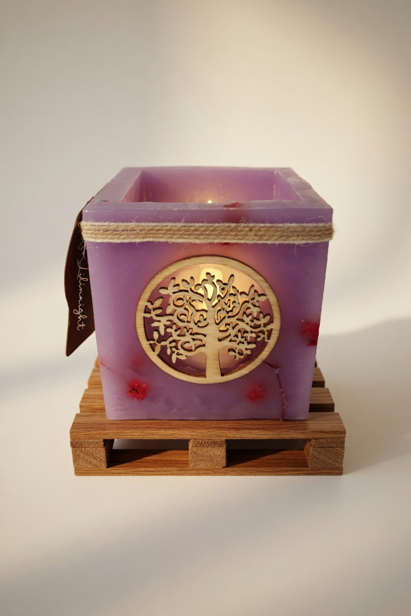 Vela hueca artesanal con símbolo del Árbol de la Vida en color lila, iluminada con luz LED cálida. Pieza única hecha a mano con flores naturales.